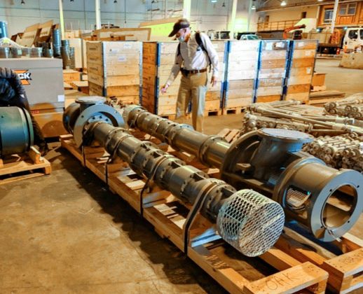 An image of two horizontal water pumps lying on the ground with a worker standing over top.