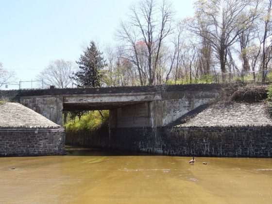 A decaying roadway bridge above a spillway and reservoir.