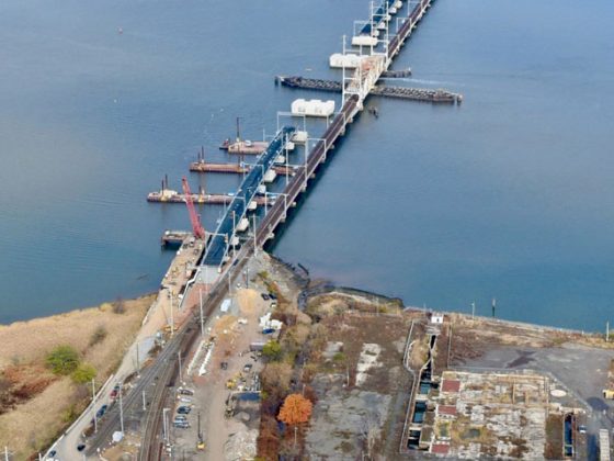 Arial image of two bridges crossing a river with a warehouse in the background.