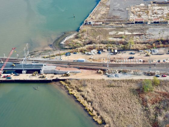Arial image of a bridge construction area with two bridges crossing into a river towards the left.