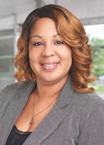 Tamika is smiling in her headshot. She is wearing a black blouse and a gray patterned suit jacket.