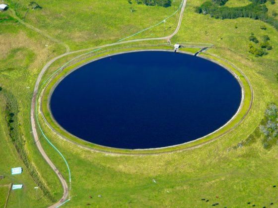 A round reservoir of blue water surrounded by grass fields on Hawaii Island.